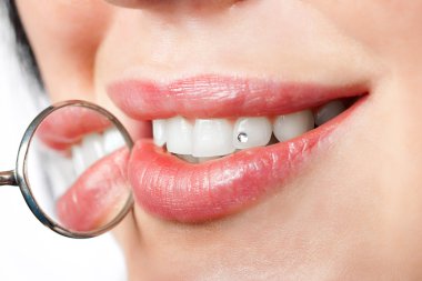 Dental mouth mirror near healthy white woman teeth with precious stone on i clipart