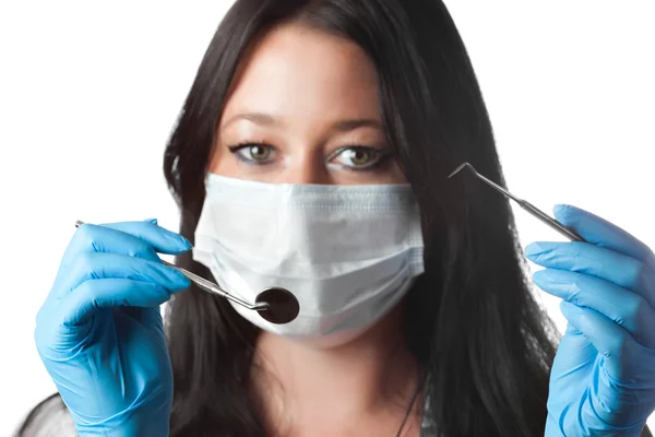 Dentista feminino em máscara segurando ferramenta e espelho isolado no branco. concentrar-se — Fotografia de Stock