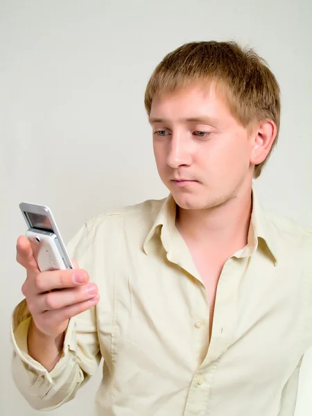 stock image The young man looks at a mobile phone