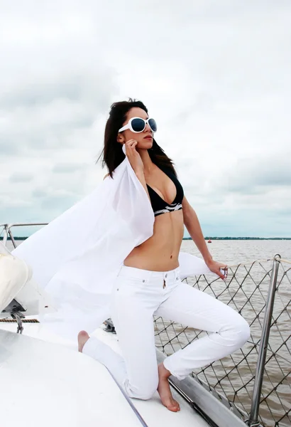 Mladá dívka v sluneční brýle na píci jachty proti — Stock fotografie