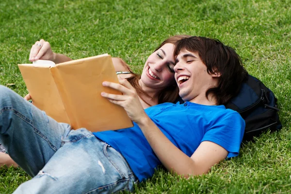 Paar studenten leggen op het gras en lezen van een boek — Stockfoto