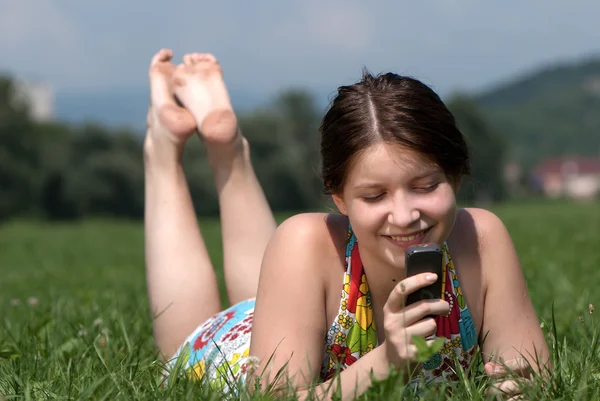 Девушка говорит по мобильному телефону против летней зеленой природы — стоковое фото