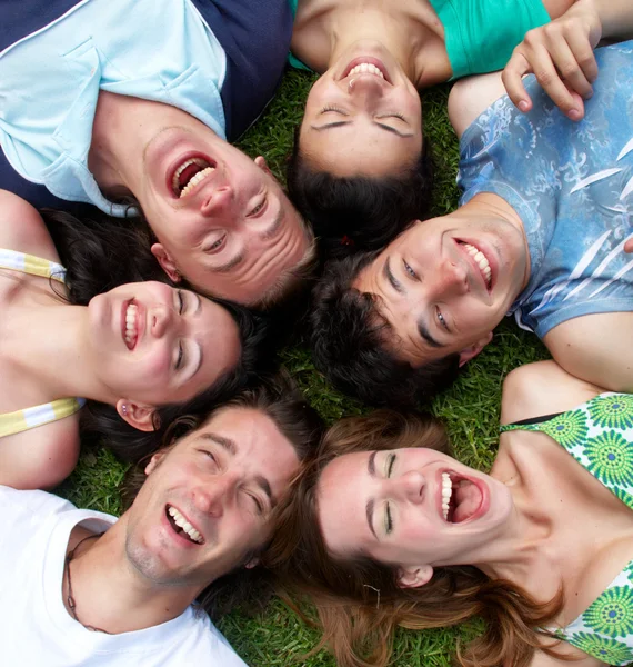Young guys and girls lying on grass looking up — Stock Photo, Image