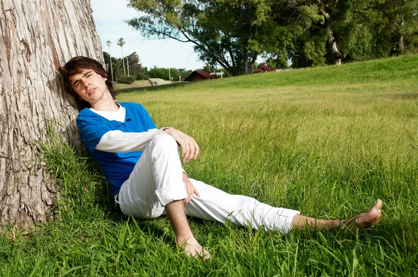 The young guy having a rest near a tree — Stock Photo, Image