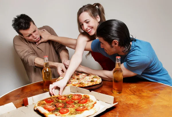 A companhia alegre de jovens que comem uma pizza — Fotografia de Stock