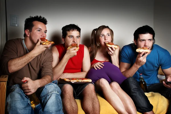 The concentrated fans with a pizza in hands, watching TV — Stock Photo, Image