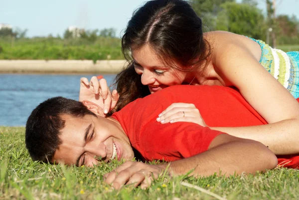 Счастливая молодая пара играет в парке на траве — стоковое фото