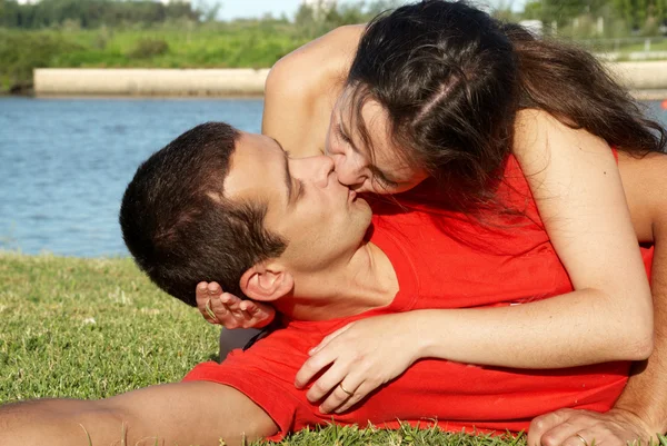 Feliz jovem casal beijando no parque na grama — Fotografia de Stock