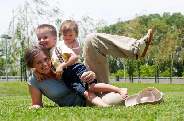 Gelukkig moeder spelen met kinderen op een gazon — Stockfoto