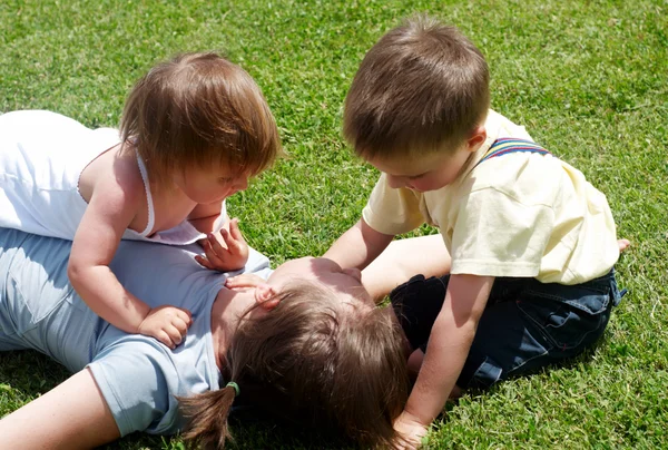 Mère heureuse jouant avec les enfants sur une pelouse — Photo