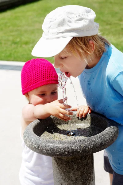 Дети пьют воду в питьевом фонтане в парке — стоковое фото