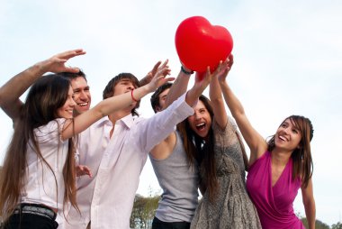 Group of young guys and girls with a sphere in the form of heart clipart