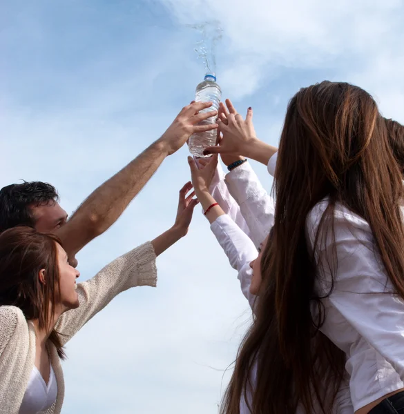 Grupp unga män sträcker händerna till en flaska med vatten — Stockfoto
