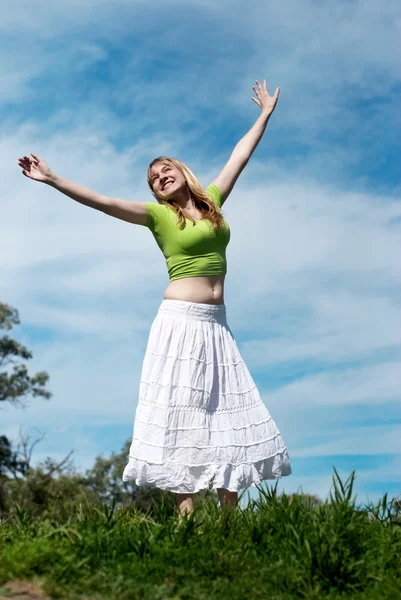 Pretty young woman with arms raised against nature — Stock Photo, Image