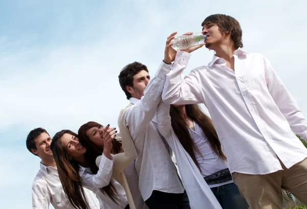 Gruppo di giovani uomini che allungano le mani a una bottiglia con acqua — Foto Stock