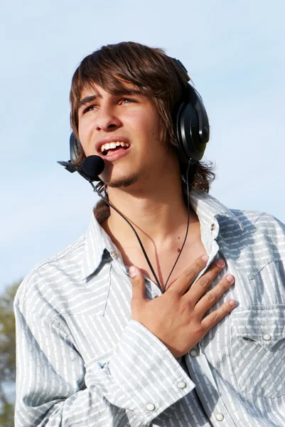 Zpívající dospívající chlapec v sluchátka proti povaze — Stock fotografie