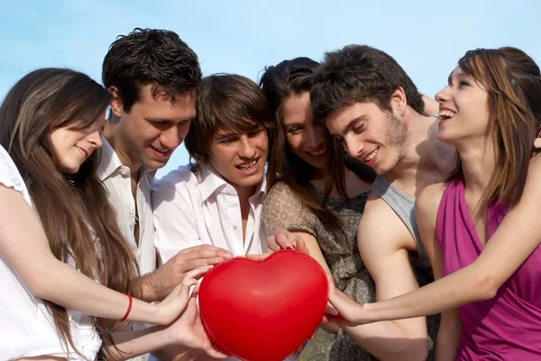 Skupina mladých kluků a dívek s koulí v podobě srdce — Stock fotografie