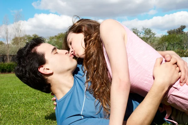 Happy νεαρό ζευγάρι φιλιά στο πάρκο στο γρασίδι — Φωτογραφία Αρχείου