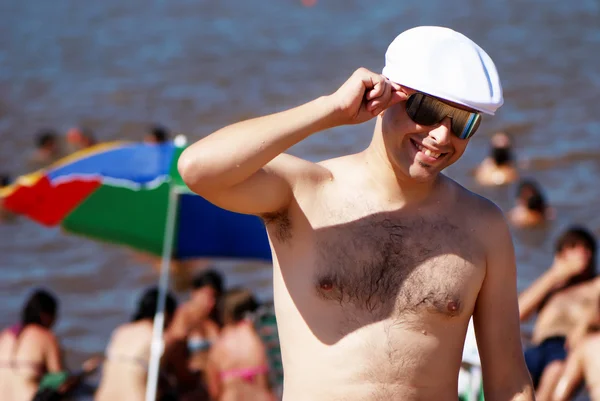 Joyeux jeune homme en lunettes de soleil sur une plage — Photo
