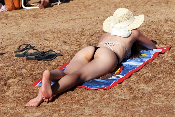 Mulher de chapéu jaz na praia — Fotografia de Stock