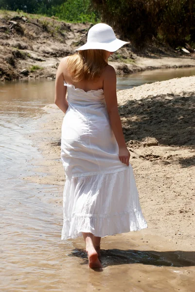 A jovem menina de branco indo na areia — Fotografia de Stock