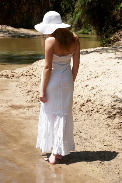 Den unge jenta i hvitt som går på sand – stockfoto