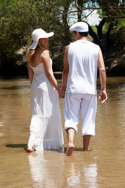 Le jeune couple en blanc va sur la rivière — Photo