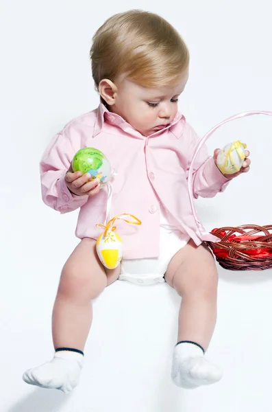 Маленький мальчик с пасхальными яйцами на белом фоне — стоковое фото