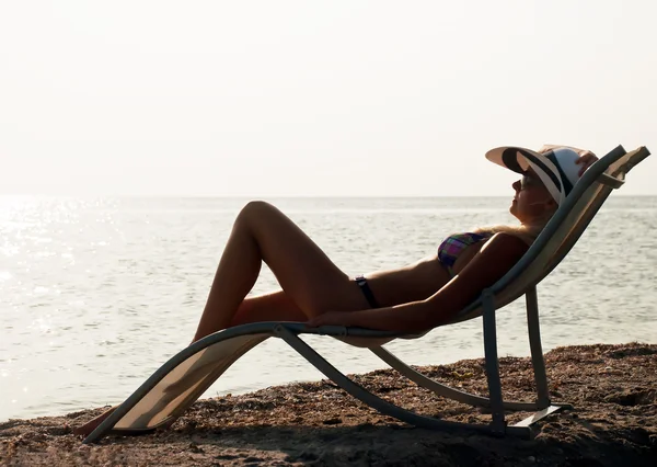 La ragazza in un cappello che ha un riposo su costa marittima — Foto Stock