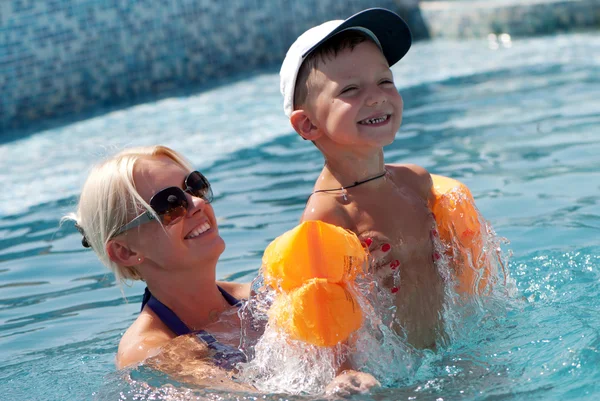 Sonriente hermosa mujer y pequeño niño se baña en la piscina —  Fotos de Stock