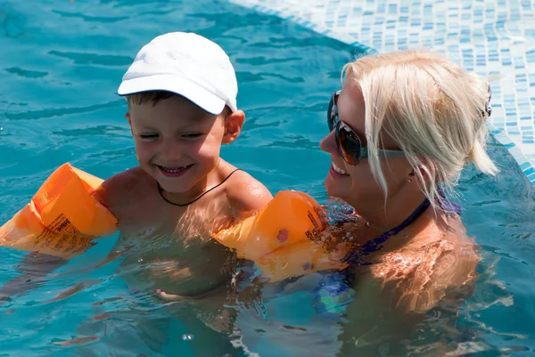 Sonriente hermosa mujer y pequeño niño se baña en la piscina — Foto de Stock