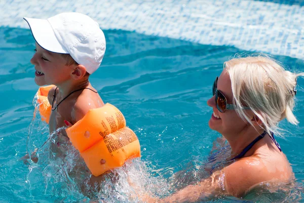 Glimlachen, mooie vrouw en kleine jongen baadt in zwembad — Stockfoto