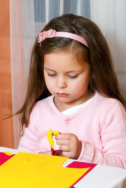 Kleines Mädchen schneidet Figuren aus einem Farbpapier — Stockfoto