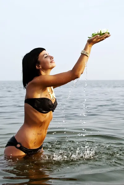 A menina com uma flor em mãos contra o mar — Fotografia de Stock