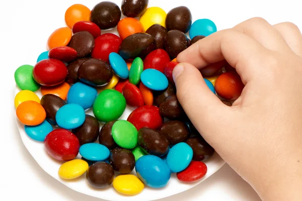 Mãos de crianças segurando caramelo de cor em um fundo claro — Fotografia de Stock