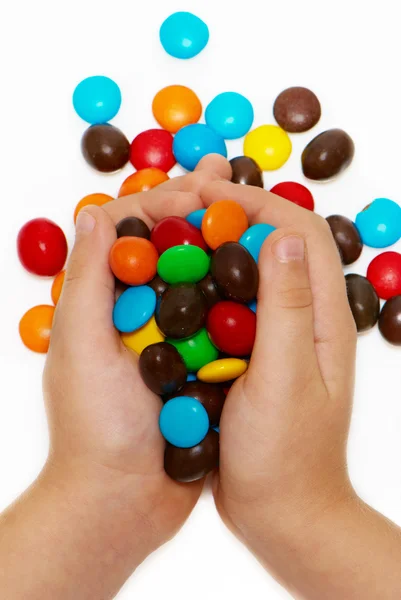Mãos de crianças segurando caramelo de cor em um fundo claro — Fotografia de Stock