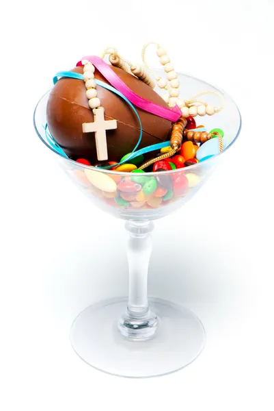 Uovo di cioccolato di Pasqua, caramelle e croce in un bicchiere su una ba leggera — Foto Stock