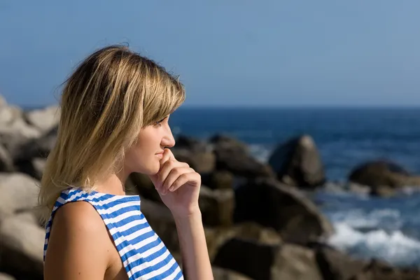 Atraktivní zamyšlená dívka na skalnaté pláži u moře. — Stock fotografie