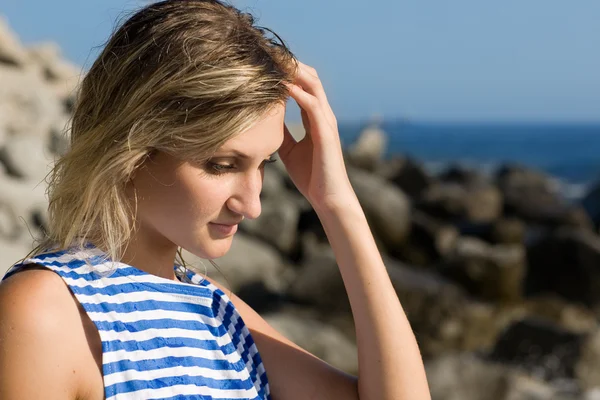 Attractive thoughtful girl on a rocky beach by the sea. — Stock Photo, Image