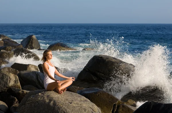 Bella ragazza in posizione loto sulla pietra. Schizzi di mare w — Foto Stock