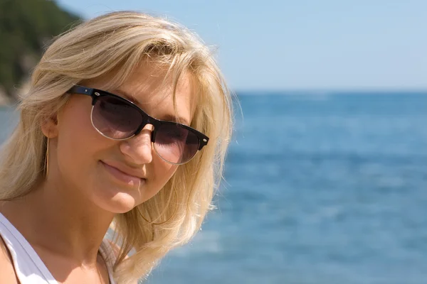 Fille heureuse portant des lunettes de soleil à la mer — Photo