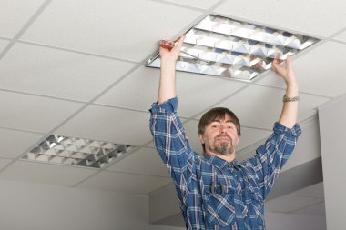 Electrician installs lighting to the ceiling. clipart