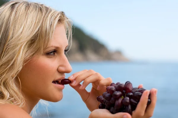 Молода жінка їсть виноград — стокове фото