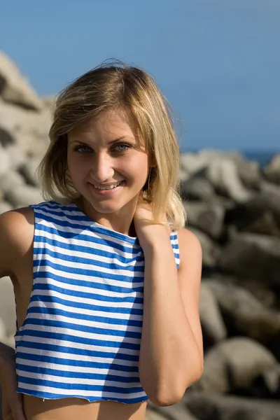 stock image Smiling girl on a rocky beach by the sea.