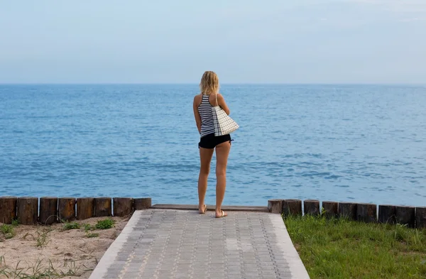 Aantrekkelijke blonde staande op het strand — Stockfoto