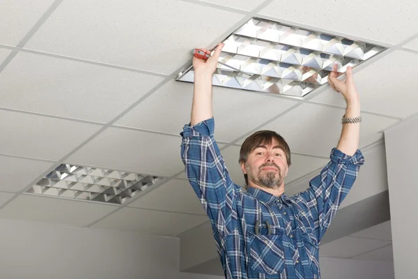 Elektricien installeert verlichting aan het plafond. — Stockfoto