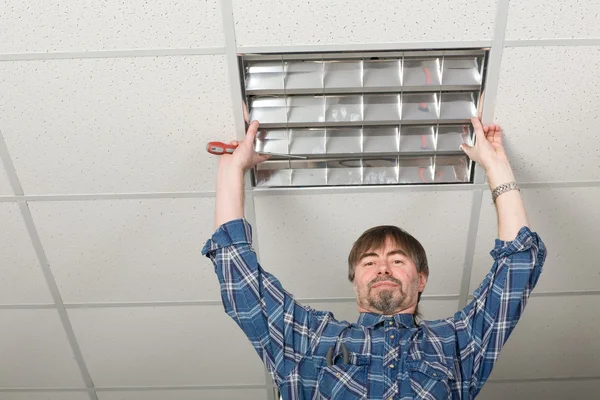 Elektricien installeert verlichting aan het plafond. — Stockfoto