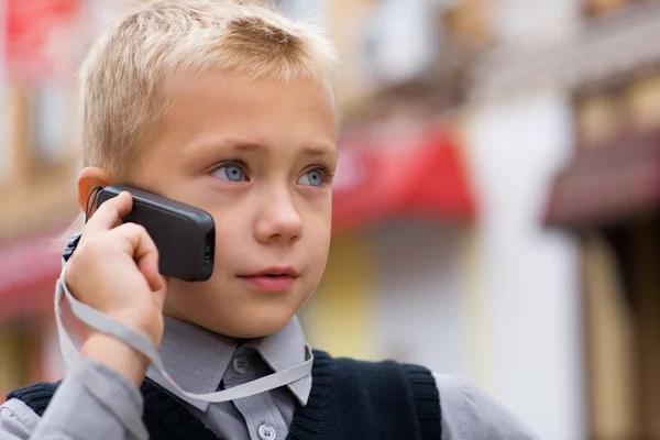 A kisfiú egy mobiltelefonon beszél — Stock Fotó
