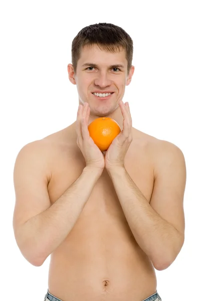 Smiling young man with an orange. — Stock Photo, Image