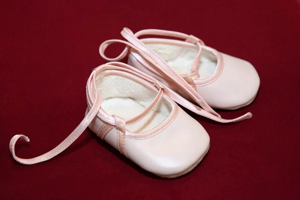 Pink baby schoenen op rood — Stockfoto